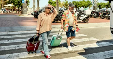 Senior couple crossing the street with suitcases that could be stolen on vacation.