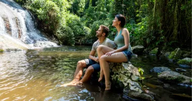 Couple looking at a waterfall may see why travel insurance is worth it during their trip