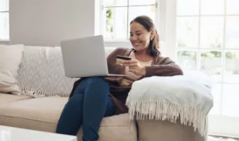 Woman holding a credit card and looking at her laptop to see how much travel insurance is for her trip