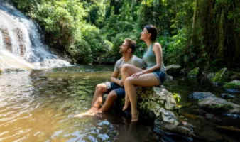 Couple looking at a waterfall may see why travel insurance is worth it during their trip