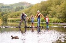 Grandparents and two children crossing a river