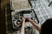 Person packing suitcase on bed