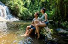 Couple looking at a waterfall may see why travel insurance is worth it during their trip