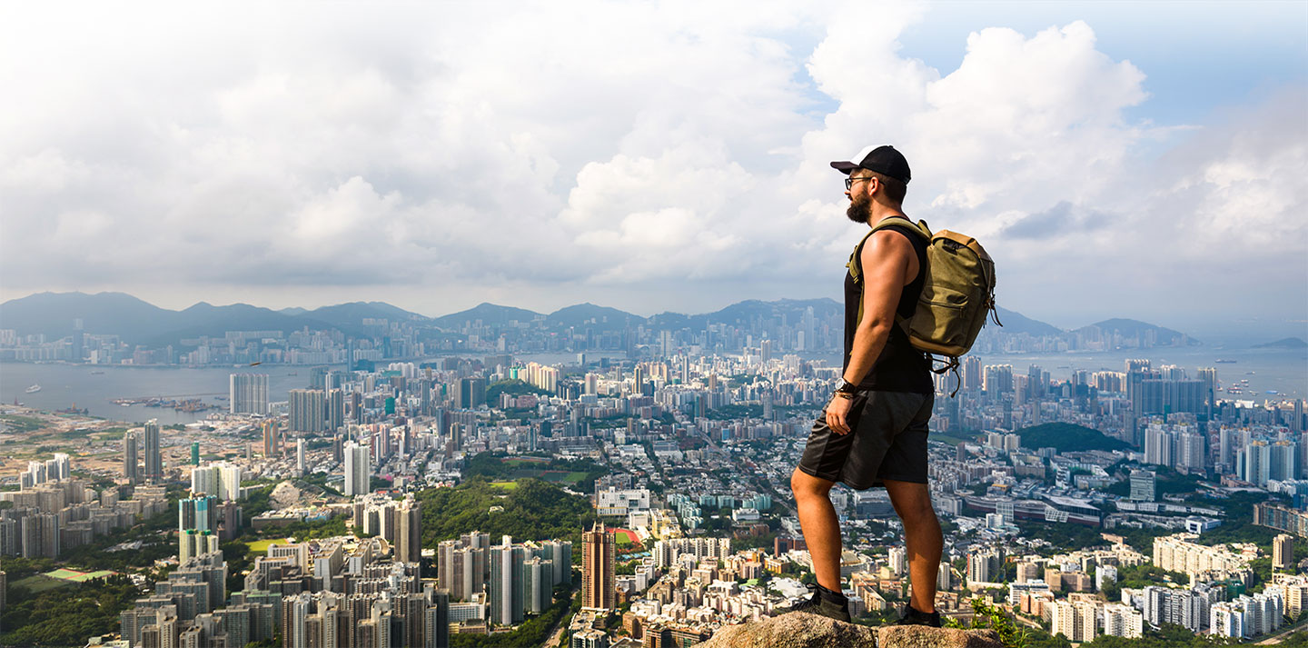 Backpacker on mountain overlooking city