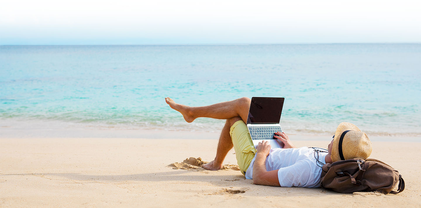 man on beach with laptop