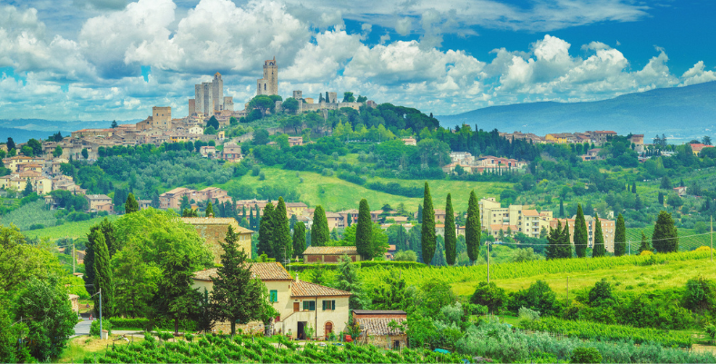 Read our Europe travel guide before you see views like this one of San Gimignano, Tuscany with homes and green hills.