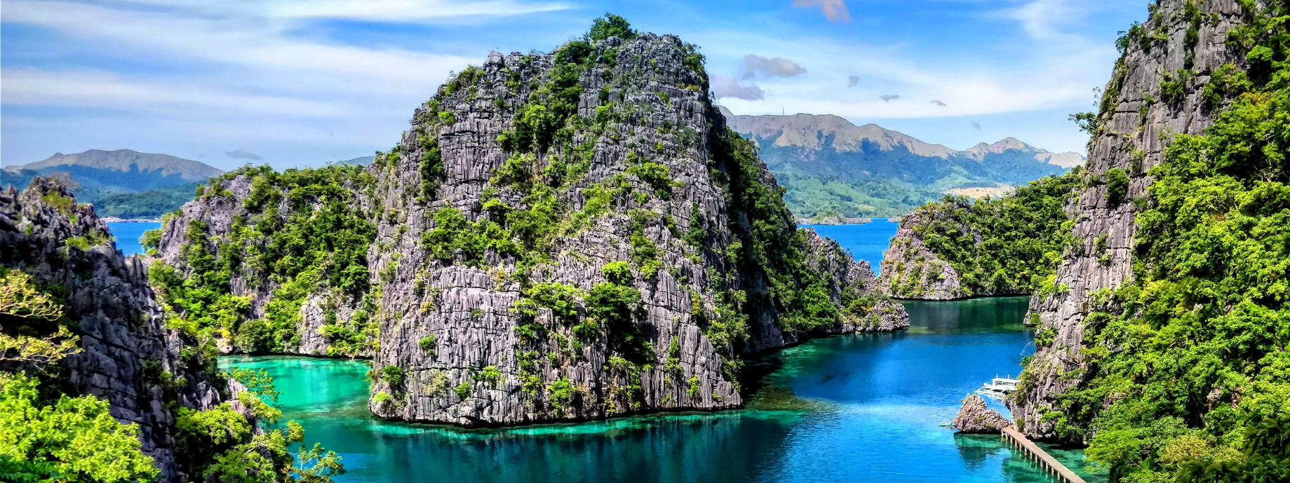 Kayangan Lake with boats and surrounding hills, where you can travel with travel insurance for the Philippines