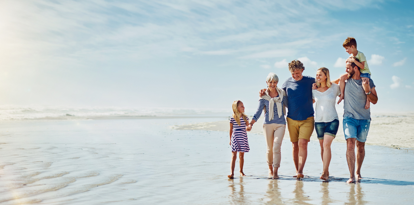 Multigenerational family walking on the beach that can choose from various types of travel insurance