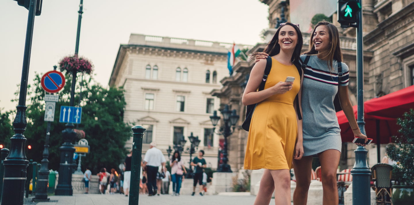 Two young women with backpacks crossing the street in Budapest with student travel insurance