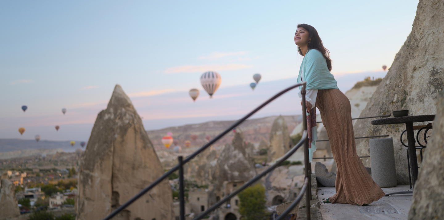 Woman traveling with affordable travel insurance watching hot air balloons in Cappadocia, Turkey