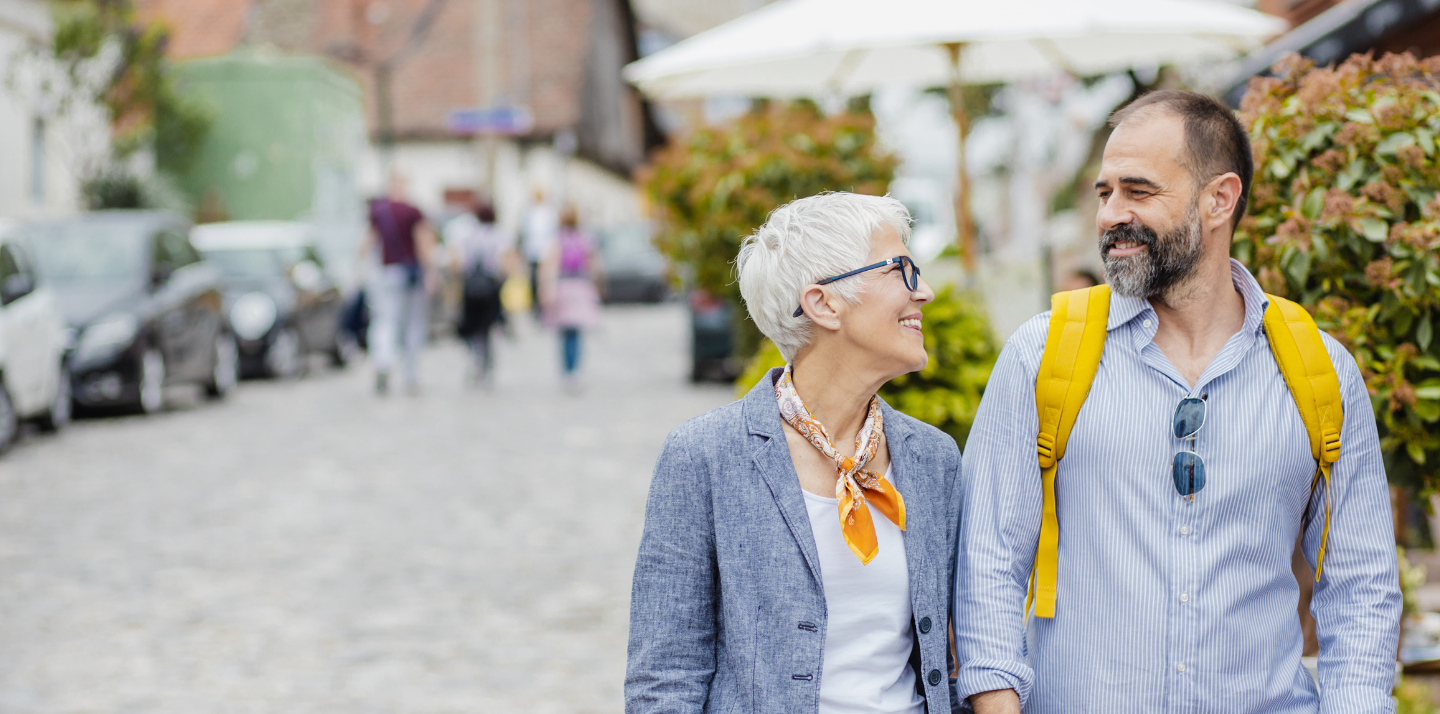 Senior couple smiling and holding hands on the street while traveling with cheap travel insurance