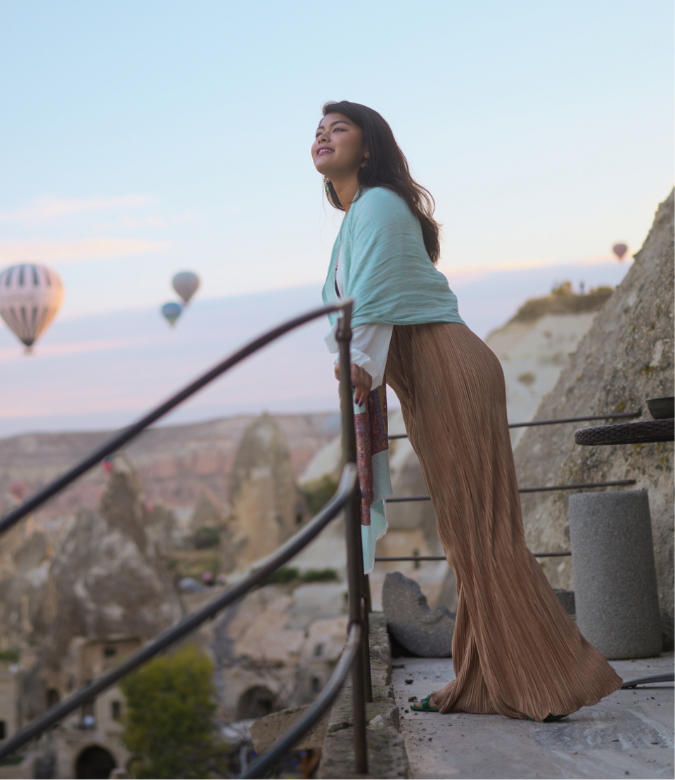 Woman traveling with affordable travel insurance watching hot air balloons in Cappadocia, Turkey