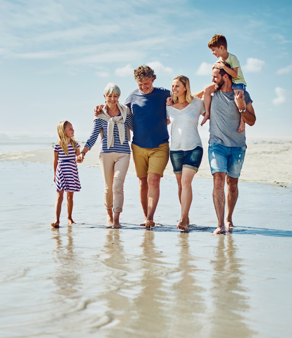 Multigenerational family walking on the beach that can choose from various types of travel insurance