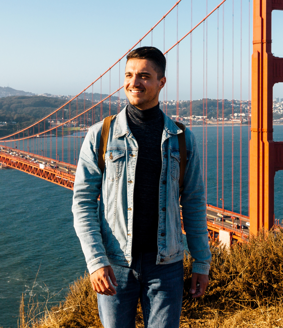 Young man with domestic travel insurance smiling with the Golden Gate Bridge in the background in San Francisco