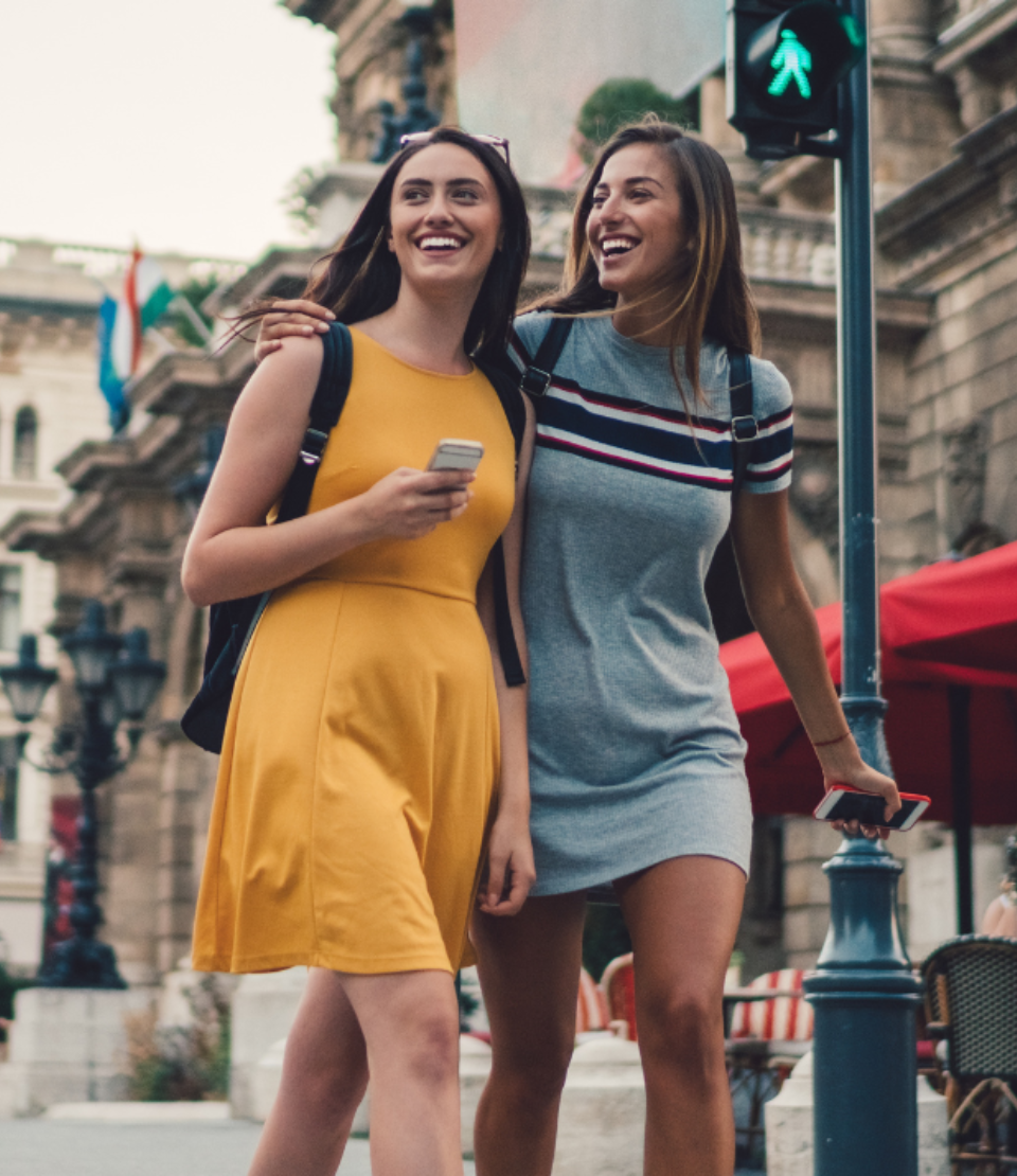 Two young women with backpacks crossing the street in Budapest with student travel insurance