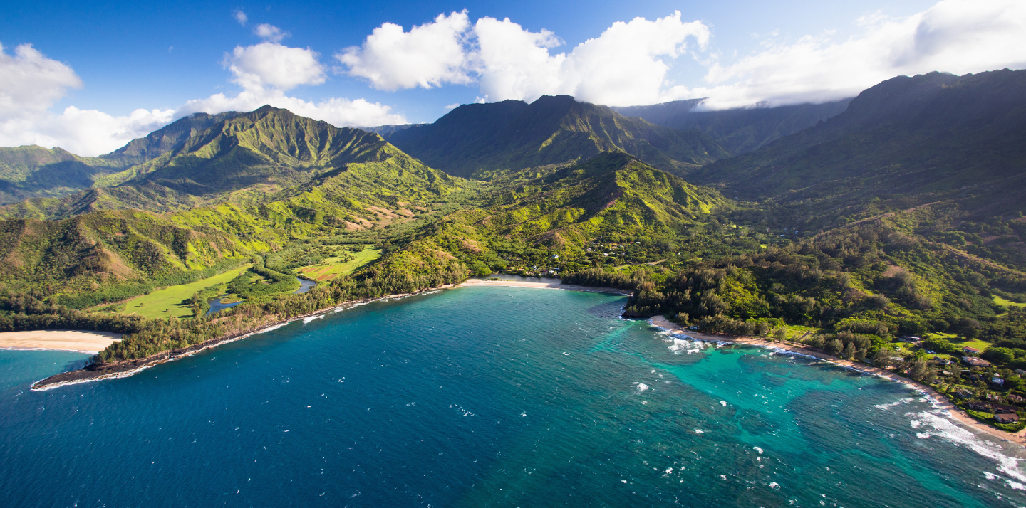 Aerial view of mountains, beach, and ocean in Kauai, where you can travel with Hawaii travel insurance