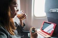 Person eating and drinking in plane seat