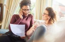 Women talking on phone and discussing paperwork