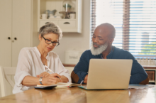 Couple using a laptop to file a claim after reading travel insurance claim tips.