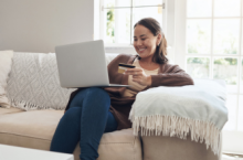 Woman holding a credit card and looking at her laptop to see how much travel insurance is for her trip