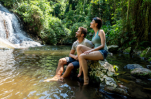 Couple looking at a waterfall may see why travel insurance is worth it during their trip