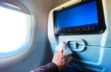 Hand wiping down airplane seatback tray