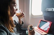 Person eating and drinking in plane seat