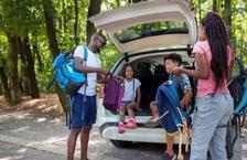 Two parents and two kids pulling backpacks out of a station wagon