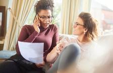 Women talking on phone and discussing paperwork