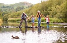 Grandparents and two children crossing a river