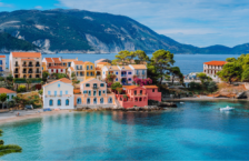 Read our Europe travel guide before traveling to see this view of Assos village in Greece with colorful houses and a lagoon.