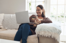 Woman holding a credit card and looking at her laptop to see how much travel insurance is for her trip