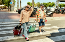 Senior couple crossing the street with suitcases that could be stolen on vacation.